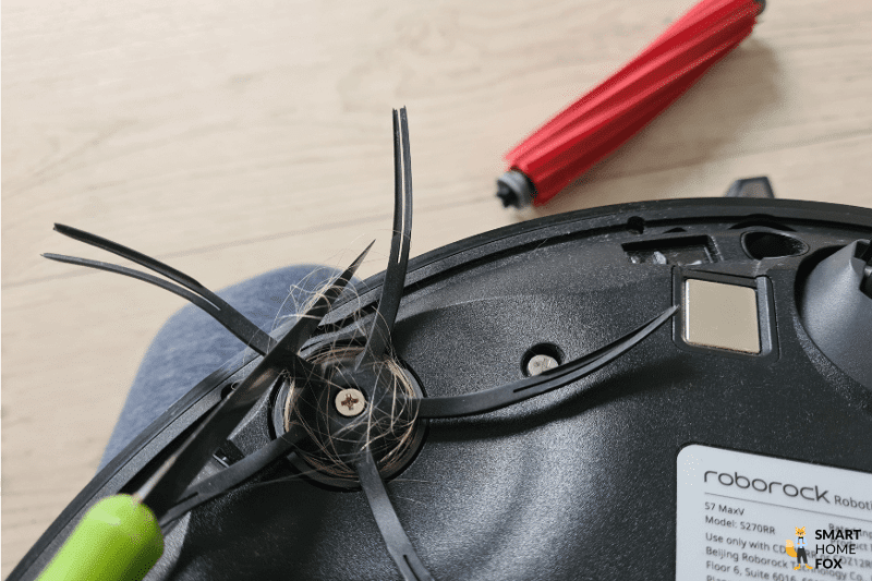 Hair has wrapped around the side brush of the Roborock S7 MaxV Ultra and is cut away with a knife.